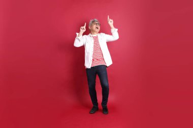 Beyaz tişörtlü üst düzey bir Doğu Asyalı koyu kırmızı arka planda duruyor..