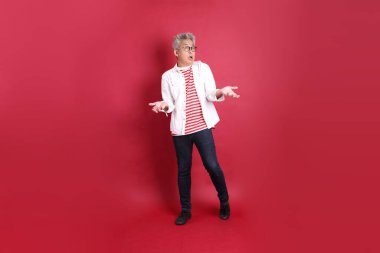 Beyaz tişörtlü üst düzey bir Doğu Asyalı koyu kırmızı arka planda duruyor..