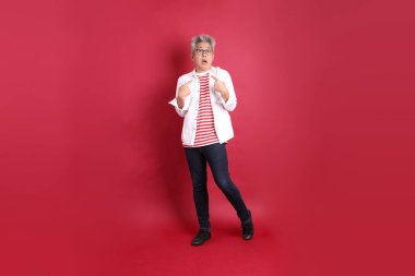 Beyaz tişörtlü üst düzey bir Doğu Asyalı koyu kırmızı arka planda duruyor..