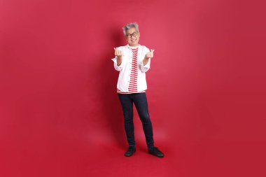 Beyaz tişörtlü üst düzey bir Doğu Asyalı koyu kırmızı arka planda duruyor..