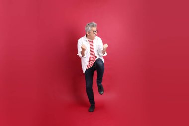 Beyaz tişörtlü üst düzey bir Doğu Asyalı koyu kırmızı arka planda duruyor..