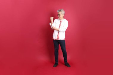 Beyaz tişörtlü üst düzey bir Doğu Asyalı koyu kırmızı arka planda duruyor..