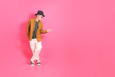 Üst düzey bir Doğu Asyalı, pembe bir arka plana karşı duruyor, renkli bir gömlek giyiyor..