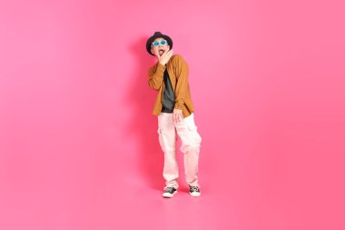 A senior East Asian man stands against a hot pink background, wearing a colorful shirt. clipart