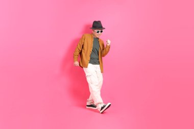 Üst düzey bir Doğu Asyalı, pembe bir arka plana karşı duruyor, renkli bir gömlek giyiyor..