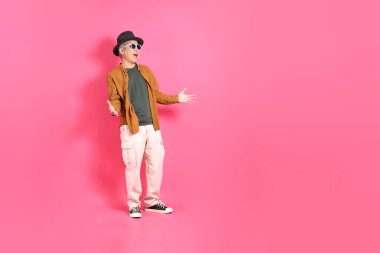 Üst düzey bir Doğu Asyalı, pembe bir arka plana karşı duruyor, renkli bir gömlek giyiyor..