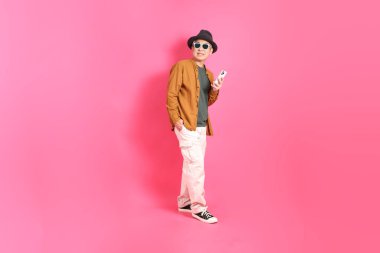 Üst düzey bir Doğu Asyalı, pembe bir arka plana karşı duruyor, renkli bir gömlek giyiyor..