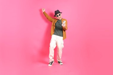 Üst düzey bir Doğu Asyalı, pembe bir arka plana karşı duruyor, renkli bir gömlek giyiyor..