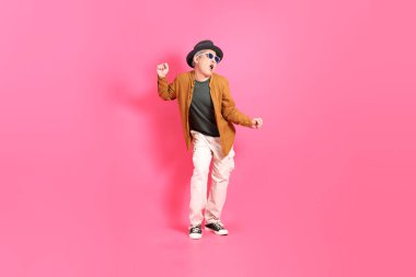 Üst düzey bir Doğu Asyalı, pembe bir arka plana karşı duruyor, renkli bir gömlek giyiyor..