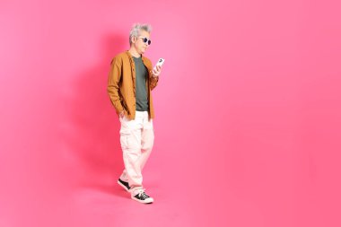 Üst düzey bir Doğu Asyalı, pembe bir arka plana karşı duruyor, renkli bir gömlek giyiyor..