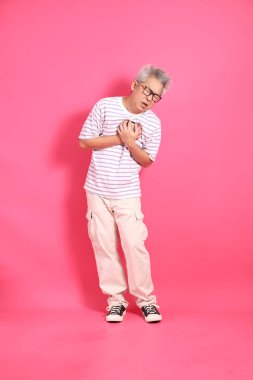 Üst düzey bir Doğu Asyalı seksi pembe bir arka plana karşı duruyor, günlük, renkli bir gömlek giyiyor..