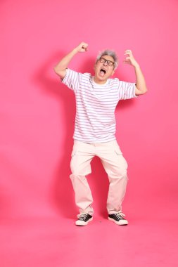 Üst düzey bir Doğu Asyalı seksi pembe bir arka plana karşı duruyor, günlük, renkli bir gömlek giyiyor..