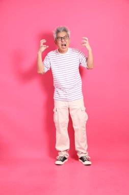 Üst düzey bir Doğu Asyalı seksi pembe bir arka plana karşı duruyor, günlük, renkli bir gömlek giyiyor..