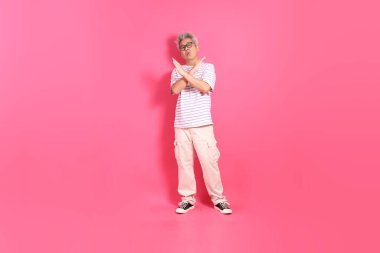 Üst düzey bir Doğu Asyalı seksi pembe bir arka plana karşı duruyor, günlük, renkli bir gömlek giyiyor..