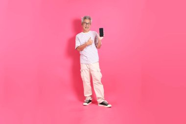 Üst düzey bir Doğu Asyalı seksi pembe bir arka plana karşı duruyor, günlük, renkli bir gömlek giyiyor..