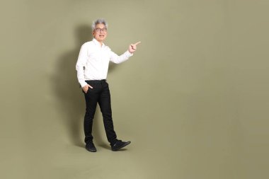 Üst düzey bir Doğu Asyalı işadamı, kıtır beyaz gömlek giymiş koyu yeşil bir arkaplanda duruyor..