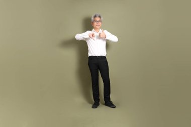 Üst düzey bir Doğu Asyalı işadamı, kıtır beyaz gömlek giymiş koyu yeşil bir arkaplanda duruyor..