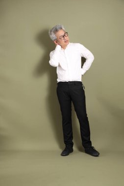 Üst düzey bir Doğu Asyalı işadamı, kıtır beyaz gömlek giymiş koyu yeşil bir arkaplanda duruyor..