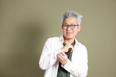 Doğu Asyalı bir işadamının yarım vücut portresi. Koyu yeşil bir arka planda izole edilmiş. Stüdyoda çekilmiş..