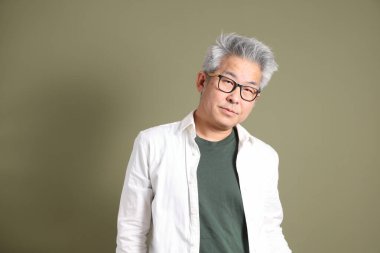 Doğu Asyalı bir işadamının yarım vücut portresi. Koyu yeşil bir arka planda izole edilmiş. Stüdyoda çekilmiş..