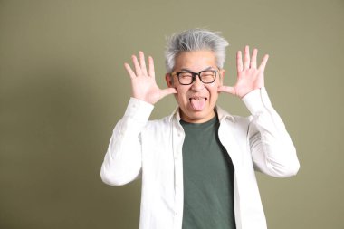 Doğu Asyalı bir işadamının yarım vücut portresi. Koyu yeşil bir arka planda izole edilmiş. Stüdyoda çekilmiş..