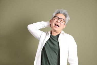 Doğu Asyalı bir işadamının yarım vücut portresi. Koyu yeşil bir arka planda izole edilmiş. Stüdyoda çekilmiş..