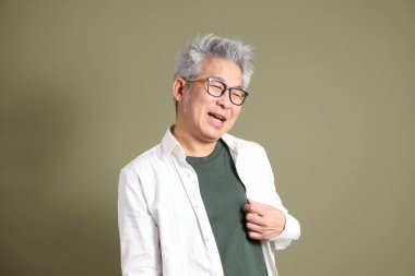 Doğu Asyalı bir işadamının yarım vücut portresi. Koyu yeşil bir arka planda izole edilmiş. Stüdyoda çekilmiş..