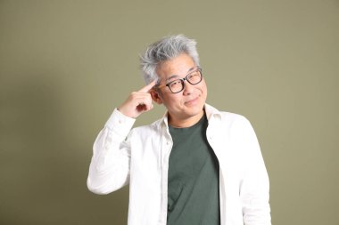 Doğu Asyalı bir işadamının yarım vücut portresi. Koyu yeşil bir arka planda izole edilmiş. Stüdyoda çekilmiş..