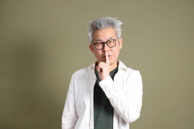 Doğu Asyalı bir işadamının yarım vücut portresi. Koyu yeşil bir arka planda izole edilmiş. Stüdyoda çekilmiş..