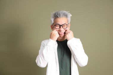 Doğu Asyalı bir işadamının yarım vücut portresi. Koyu yeşil bir arka planda izole edilmiş. Stüdyoda çekilmiş..