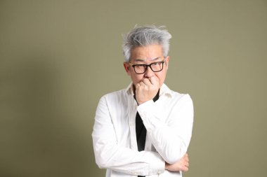 Doğu Asyalı bir işadamının yarım vücut portresi. Koyu yeşil bir arka planda izole edilmiş. Stüdyoda çekilmiş..