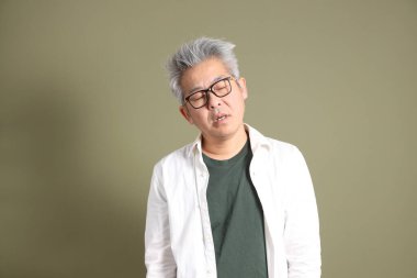 Doğu Asyalı bir işadamının yarım vücut portresi. Koyu yeşil bir arka planda izole edilmiş. Stüdyoda çekilmiş..