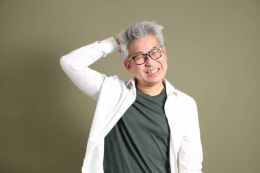 Doğu Asyalı bir işadamının yarım vücut portresi. Koyu yeşil bir arka planda izole edilmiş. Stüdyoda çekilmiş..