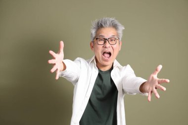 Doğu Asyalı bir işadamının yarım vücut portresi. Koyu yeşil bir arka planda izole edilmiş. Stüdyoda çekilmiş..