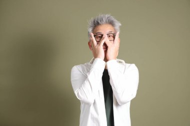 Doğu Asyalı bir işadamının yarım vücut portresi. Koyu yeşil bir arka planda izole edilmiş. Stüdyoda çekilmiş..