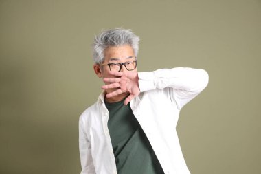 Doğu Asyalı bir işadamının yarım vücut portresi. Koyu yeşil bir arka planda izole edilmiş. Stüdyoda çekilmiş..