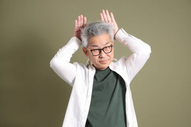 Doğu Asyalı bir işadamının yarım vücut portresi. Koyu yeşil bir arka planda izole edilmiş. Stüdyoda çekilmiş..