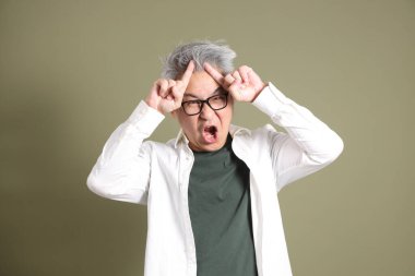 Doğu Asyalı bir işadamının yarım vücut portresi. Koyu yeşil bir arka planda izole edilmiş. Stüdyoda çekilmiş..