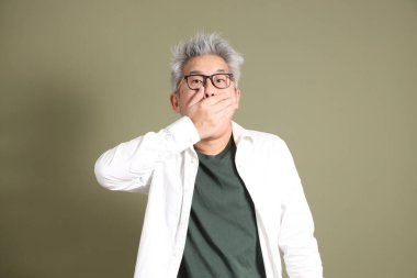 Doğu Asyalı bir işadamının yarım vücut portresi. Koyu yeşil bir arka planda izole edilmiş. Stüdyoda çekilmiş..