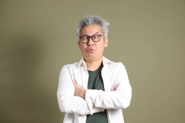 Doğu Asyalı bir işadamının yarım vücut portresi. Koyu yeşil bir arka planda izole edilmiş. Stüdyoda çekilmiş..