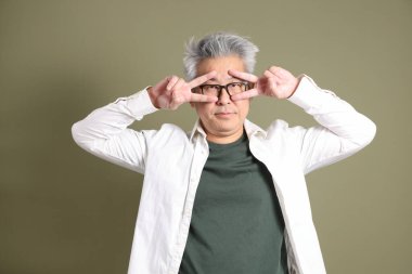 Doğu Asyalı bir işadamının yarım vücut portresi. Koyu yeşil bir arka planda izole edilmiş. Stüdyoda çekilmiş..