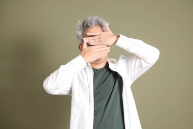 Doğu Asyalı bir işadamının yarım vücut portresi. Koyu yeşil bir arka planda izole edilmiş. Stüdyoda çekilmiş..