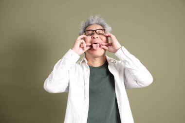 Doğu Asyalı bir işadamının yarım vücut portresi. Koyu yeşil bir arka planda izole edilmiş. Stüdyoda çekilmiş..