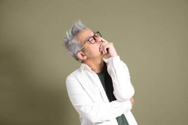 Doğu Asyalı bir işadamının yarım vücut portresi. Koyu yeşil bir arka planda izole edilmiş. Stüdyoda çekilmiş..