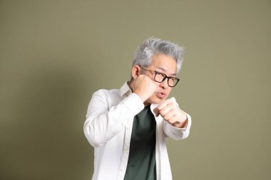 Doğu Asyalı bir işadamının yarım vücut portresi. Koyu yeşil bir arka planda izole edilmiş. Stüdyoda çekilmiş..