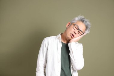 Doğu Asyalı bir işadamının yarım vücut portresi. Koyu yeşil bir arka planda izole edilmiş. Stüdyoda çekilmiş..