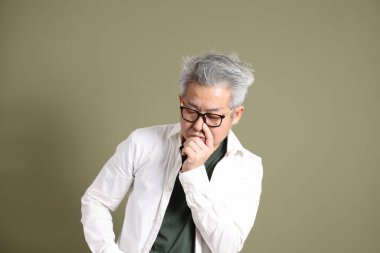 Doğu Asyalı bir işadamının yarım vücut portresi. Koyu yeşil bir arka planda izole edilmiş. Stüdyoda çekilmiş..