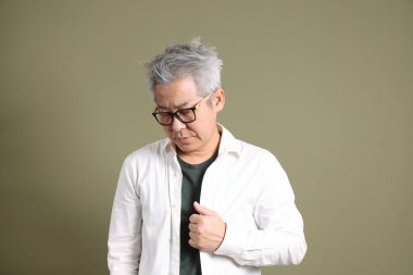 Doğu Asyalı bir işadamının yarım vücut portresi. Koyu yeşil bir arka planda izole edilmiş. Stüdyoda çekilmiş..