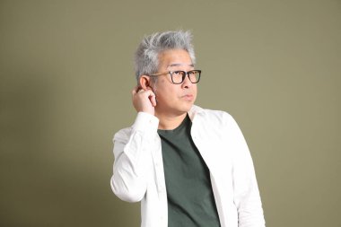 Doğu Asyalı bir işadamının yarım vücut portresi. Koyu yeşil bir arka planda izole edilmiş. Stüdyoda çekilmiş..