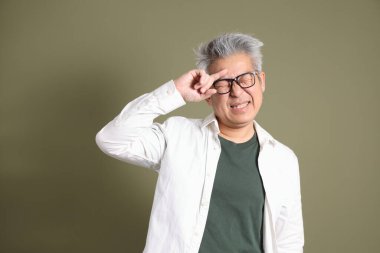 Doğu Asyalı bir işadamının yarım vücut portresi. Koyu yeşil bir arka planda izole edilmiş. Stüdyoda çekilmiş..